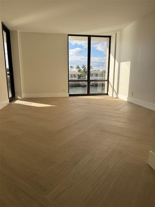 unfurnished room with a water view and a wall of windows