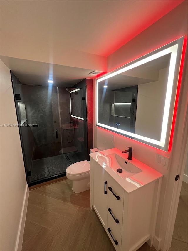 bathroom featuring a shower with door, vanity, and toilet