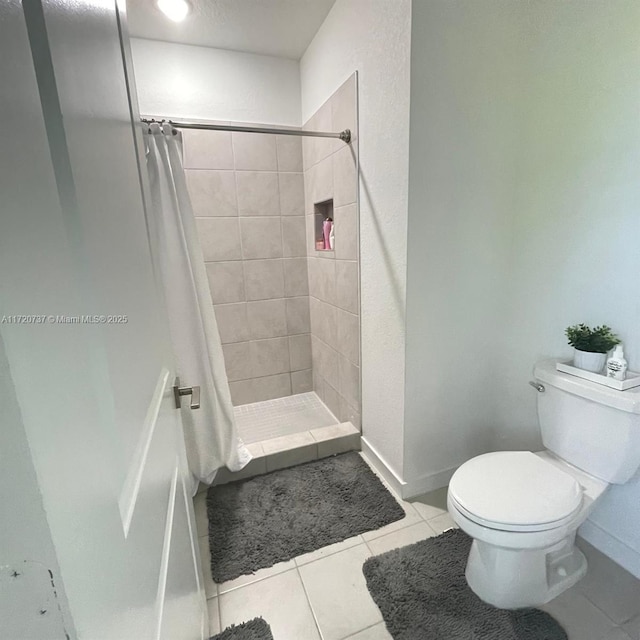 bathroom with tile patterned floors, toilet, and curtained shower