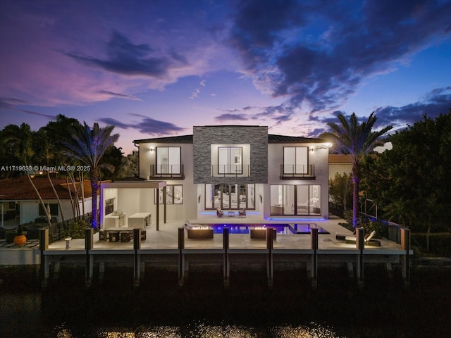 back house at dusk featuring a patio area and a balcony