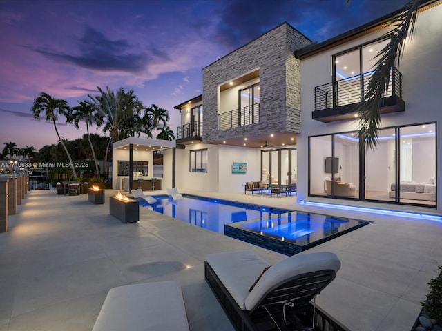 view of pool with a patio, area for grilling, an outdoor living space with a fire pit, and a pool with connected hot tub