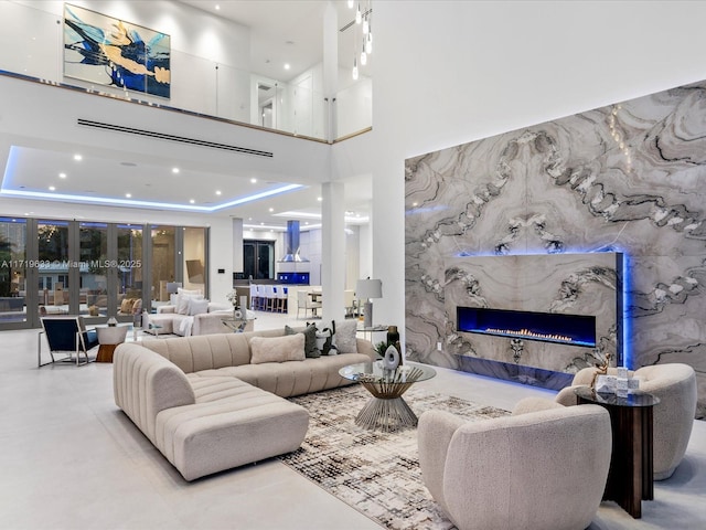 living area with recessed lighting, a raised ceiling, a fireplace, and a high ceiling