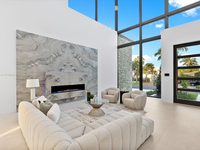 living area with a high ceiling, a wall of windows, and a fireplace