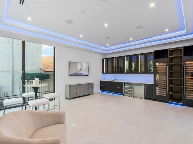 living area featuring wine cooler, a raised ceiling, and indoor wet bar