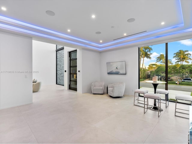 interior space featuring baseboards, ornamental molding, a raised ceiling, and recessed lighting