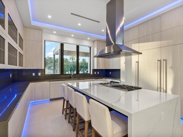 kitchen featuring a spacious island, light stone countertops, island range hood, and modern cabinets