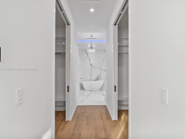 spacious closet with visible vents, a notable chandelier, and wood finished floors