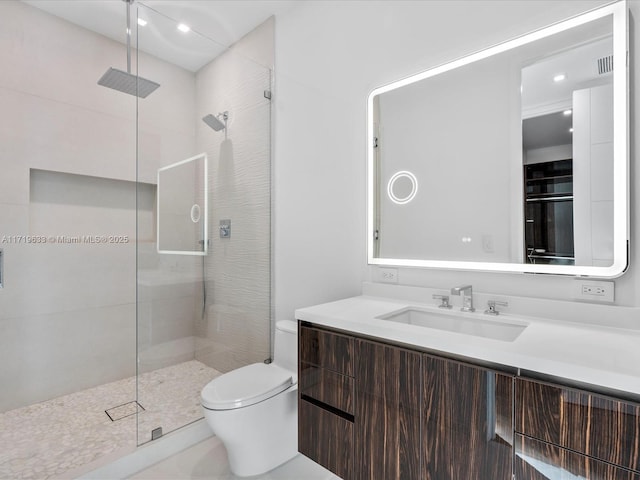 bathroom featuring tiled shower, vanity, and toilet