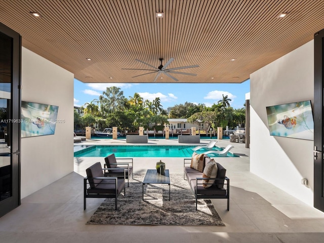 outdoor pool featuring a patio area, an outdoor living space, and a ceiling fan