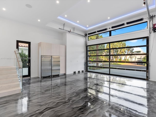 interior space with recessed lighting, a garage, a towering ceiling, marble finish floor, and a tray ceiling