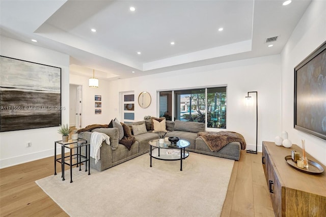 living room with a tray ceiling and light hardwood / wood-style floors