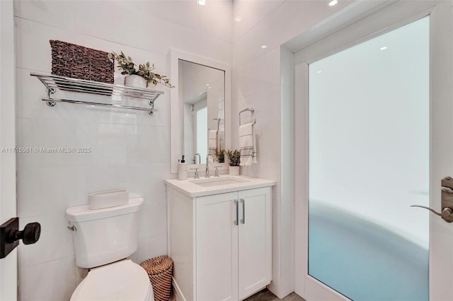 bathroom with vanity, tile walls, and toilet