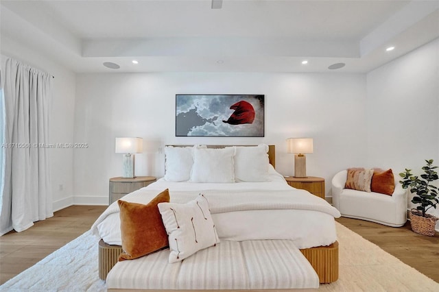 bedroom featuring light wood-type flooring and a tray ceiling