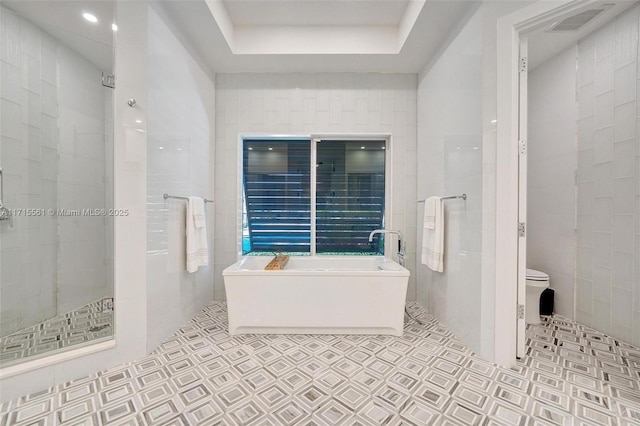 bathroom with tile patterned flooring, separate shower and tub, tile walls, and toilet