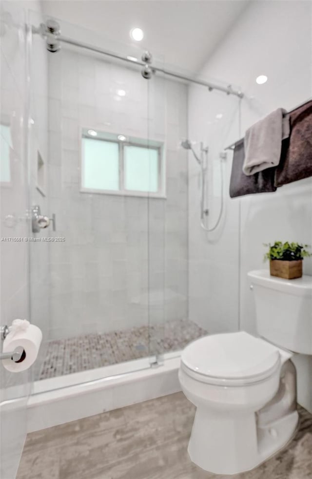 bathroom with a shower with door and toilet