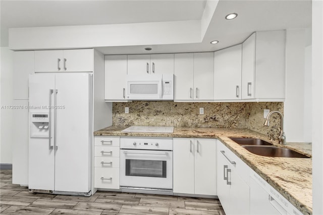 kitchen with sink, light stone counters, white appliances, decorative backsplash, and white cabinets