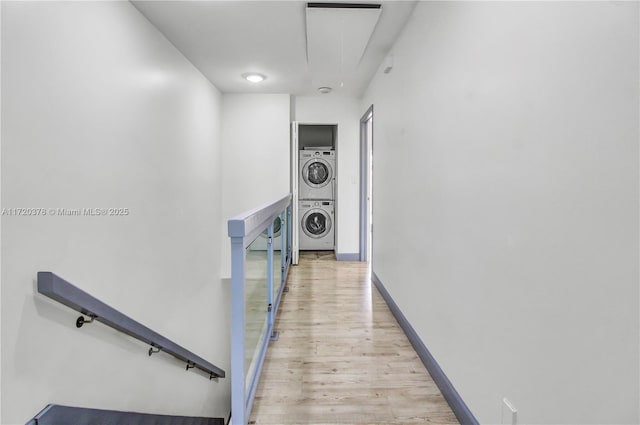 hall with light hardwood / wood-style floors and stacked washer / dryer