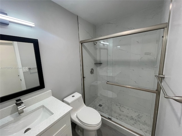 bathroom featuring vanity, toilet, and a shower with shower door