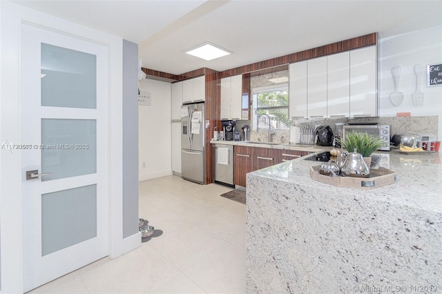 kitchen featuring sink, light stone countertops, tasteful backsplash, white cabinetry, and stainless steel appliances