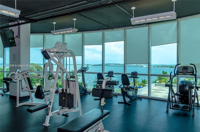 exercise room with floor to ceiling windows and a water view