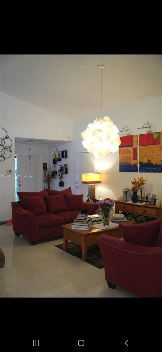 tiled living room featuring vaulted ceiling and an inviting chandelier