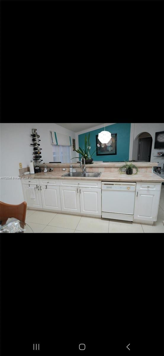 kitchen with dishwasher, sink, light tile patterned flooring, decorative light fixtures, and white cabinets