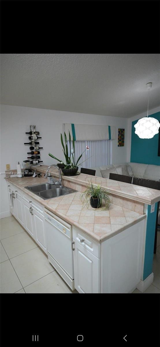 kitchen featuring dishwasher, sink, light tile patterned floors, pendant lighting, and white cabinets