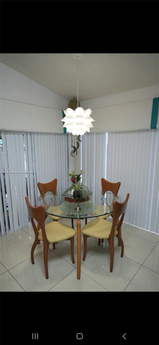 dining room featuring vaulted ceiling, an inviting chandelier, and tile patterned floors