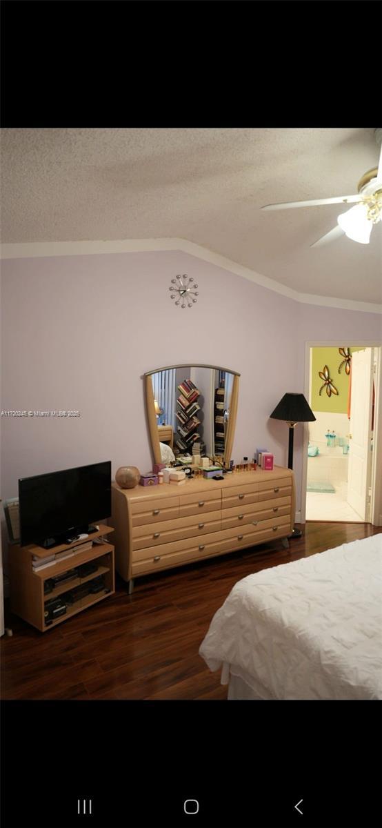 bedroom featuring ensuite bath, vaulted ceiling, ceiling fan, crown molding, and dark hardwood / wood-style floors