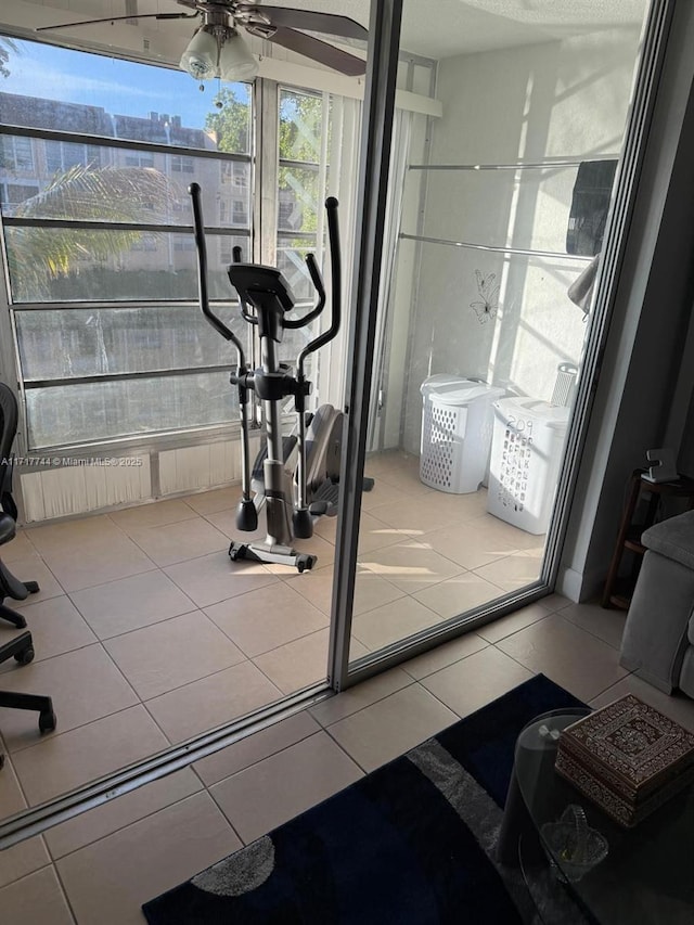 exercise room with ceiling fan and tile patterned flooring