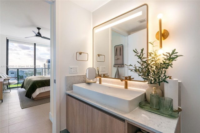 bathroom with tile patterned floors, ceiling fan, vanity, and a wall of windows