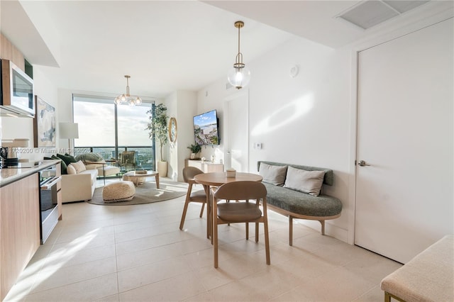 dining room featuring floor to ceiling windows, light tile patterned flooring, and an inviting chandelier