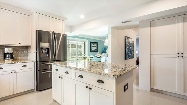 1524 39th St, West Palm Beach, FL 33407 - kitchen featuring stainless steel refrigerator with ice dispenser, decorative backsplash, light stone counters, light tile patterned floors, and ornamental molding