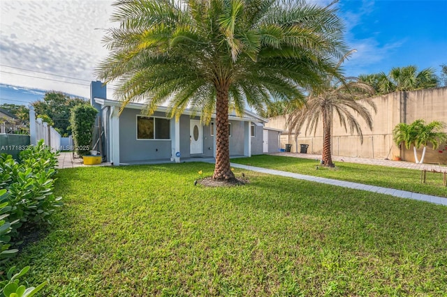 view of front of property featuring fence, a front lawn, and stucco siding