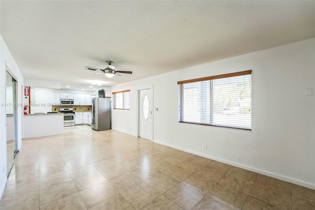 unfurnished living room with baseboards, a ceiling fan, and a healthy amount of sunlight