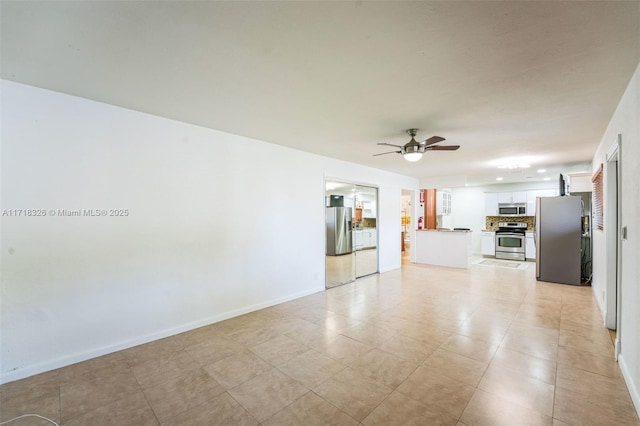 interior space with a ceiling fan and baseboards