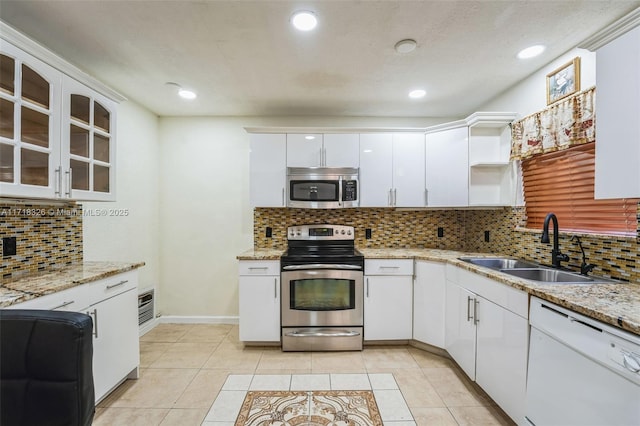 kitchen featuring light tile patterned floors, glass insert cabinets, stainless steel appliances, white cabinetry, and a sink