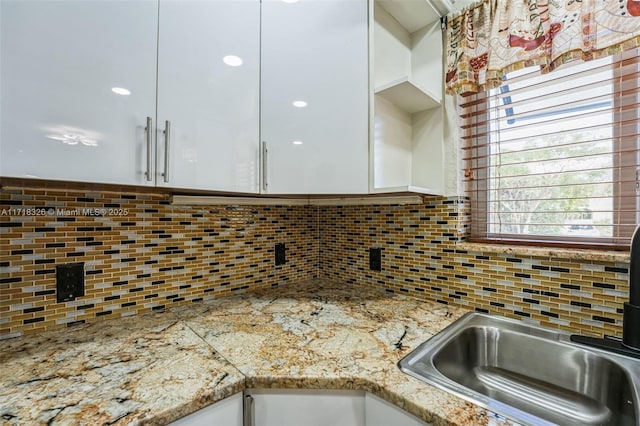 kitchen with light stone countertops, tasteful backsplash, and white cabinets