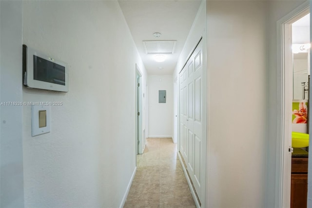 hall with attic access, electric panel, and baseboards