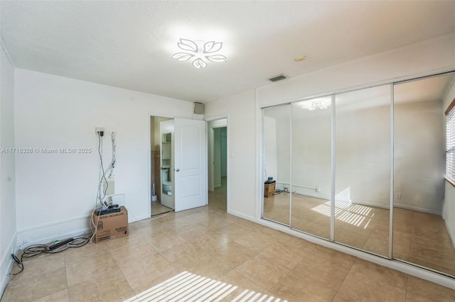 unfurnished bedroom featuring light tile patterned floors, a closet, visible vents, and baseboards