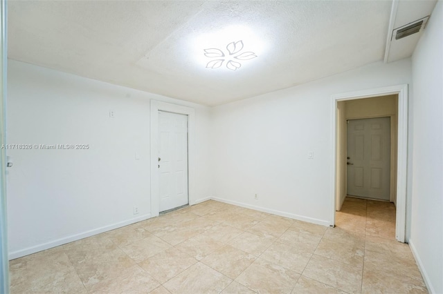 unfurnished room with visible vents, a textured ceiling, and baseboards