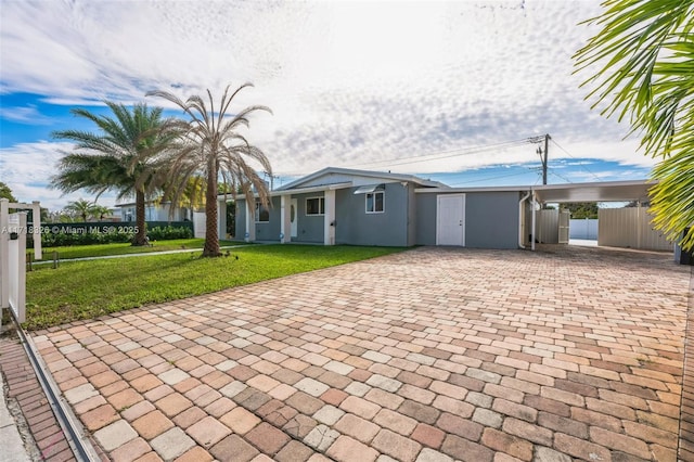 view of front facade with fence, decorative driveway, stucco siding, a carport, and a front yard