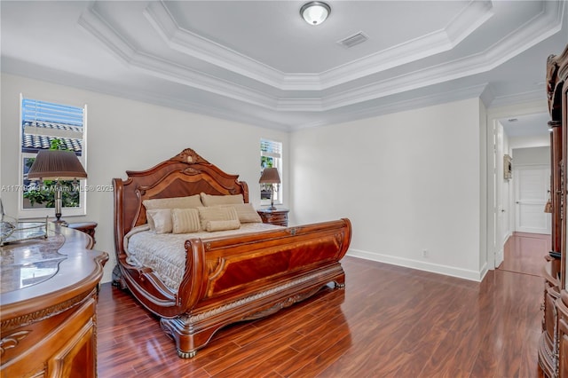 bedroom featuring ornamental molding, a tray ceiling, and dark wood-type flooring