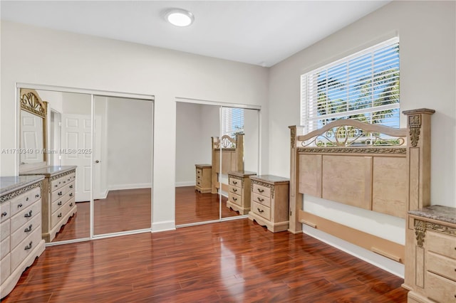 bedroom with multiple closets and dark hardwood / wood-style floors