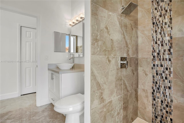 bathroom with a tile shower, vanity, and toilet