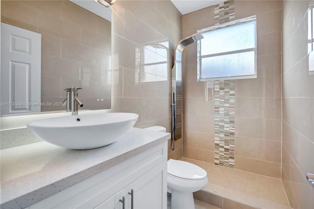 bathroom featuring toilet, vanity, tile walls, and tiled shower