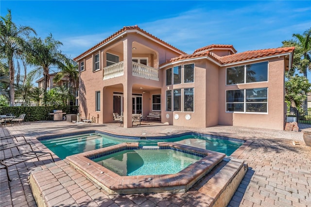 back of house with a pool with hot tub, a patio area, and a balcony