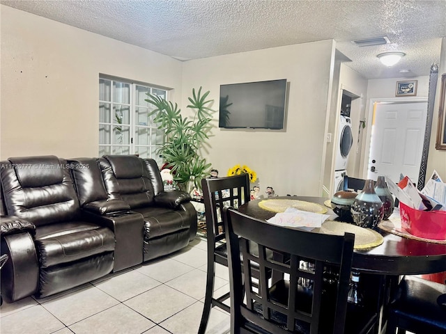 dining room with a textured ceiling, stacked washer and dryer, and light tile patterned flooring