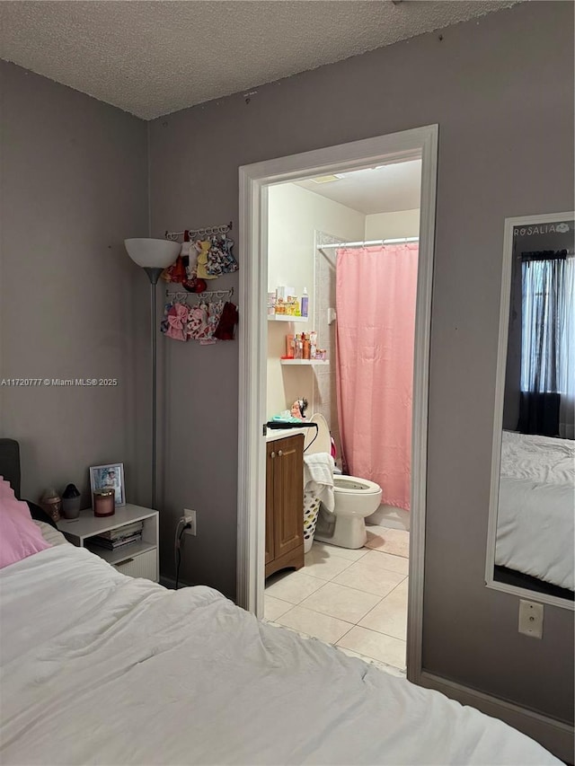 bedroom with light tile patterned floors, a textured ceiling, and connected bathroom