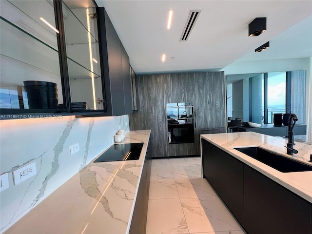 kitchen with modern cabinets, visible vents, a sink, dark cabinetry, and black electric stovetop
